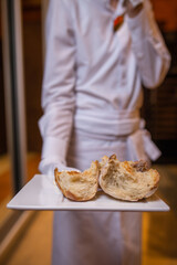 the waiter holds a crusty bread on a plate