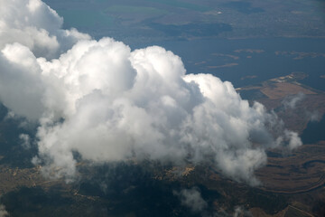 Aerial view from airplane window of white puffy clouds on bright sunny day