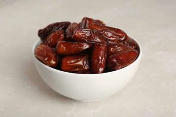 Sweet dried dates in bowl on light table