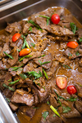close-up of beef stew with herbs in a metal container