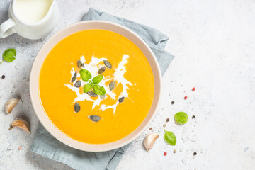 Traditionl Pumpkin soup puree with cream. Top view image at white table.