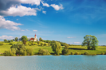 Obraz premium Church on the hill with lake in foreground. Bysicka church near SPA town Lazne Belohrad, Czech Republic.