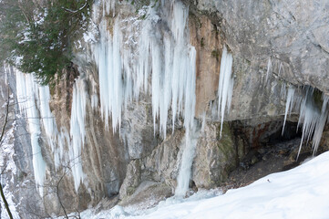 Fototapeta na wymiar Eiszapfen an einem Felsen mit einer Höhle, leicht von oben herab
