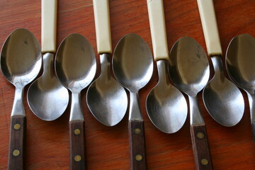Juego de cucharas de utensilios de cocina de metal forma un diseño gráfico en la mesa de madera.