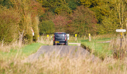 black Ford Transit Custom van driving through scenic autumnal countryside