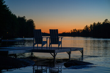 Outdoor sunbeds on the pier with a beautiful view to the lake and dense forest at sunset