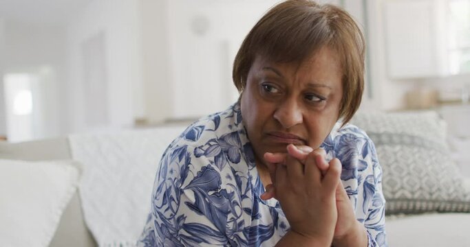 Thoughtful african american senior woman sitting with hands clasped, looking away