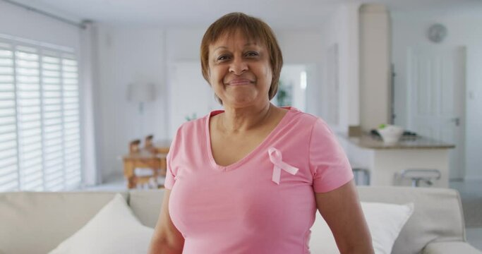 Portrait of smiling african american senior woman wearing pink t shirt and pink breast cancer ribbon