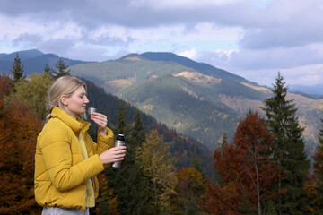 Young woman with drinking hot beverage in mountains