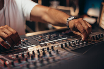 Senior hispanic music producer working on a mixing soundboard while in his studio