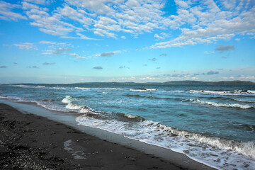 A sandy seashore with an incoming surf wave. Copy space.
