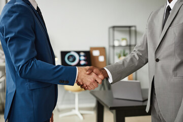 Side view shot of two businessmen shaking hands after successful deal in office, copy space