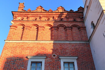 Fasada – efektowna elewacja budynku, o dużej dekoracyjności z czerwonej cegły. Facade - an impressive building facade made of red bricks with a high level of decoration.