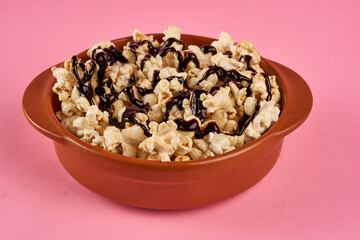 popcorn bowl with chocolate sauce on a pink background
