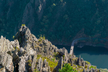 High angle view. Rocky landscape of the Ribeira Sacra taken from a viewpoint, with the River Sil below, which is crossed by a bridge with a car driving over it. Cliff. 
