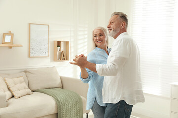 Happy senior couple dancing together in living room