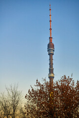 Fototapeta premium The top part of Ostankino TV tower in Moscow in orange sun sunset light and against blue sky. Travel to the capital of Russia. Moscow, Russia.