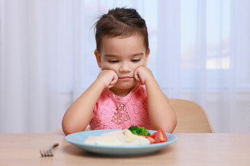 Cute little girl refusing to eat her breakfast at home
