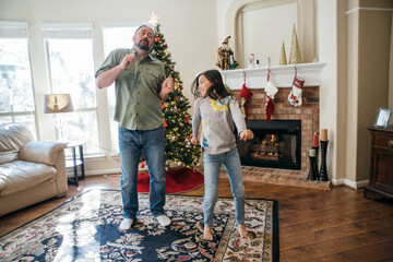 Dad and daughter dancing in living room in front of Christmas Tree and fireplace