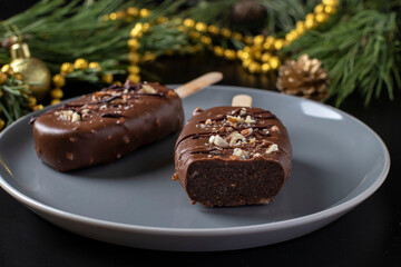 Chocolate popsicle cakes with nuts on a stick on a gray plate on dark background. Closeup