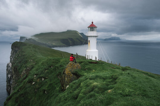 Guy enjoys the view of the lighthouse of Mykines Island, Faroe Islands