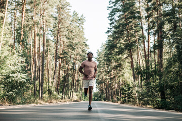 African American man, runner running on trail in the forest,Man with headphones running in the park in the morning,