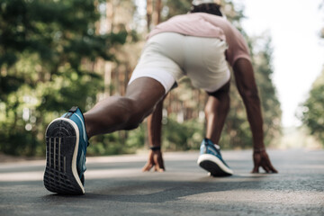 black male sprinter, in starting position ready to run, Male athlete about to start sprint outdoors...