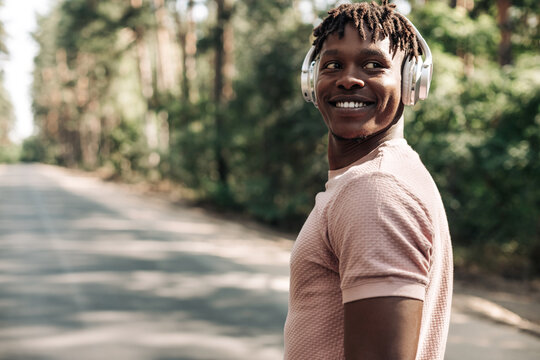 Black sporty man, listening to music on headphones during morning workout, African American man exer