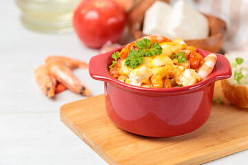 Garides Saganaki, prawns baked with cheese and vegetables in a red pot. Greek national cuisine. Close-up, selective focus