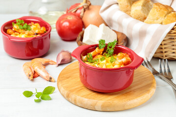 Cretan shrimp. Greek appetizer, shrimp baked in pots with cheese and vegetables. Close-up on a light background, selective focus