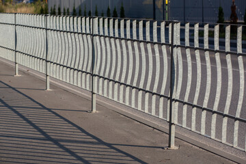 A metal fence near the road on the street protects the sidewalk