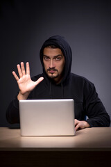 Young male hacker on grey background