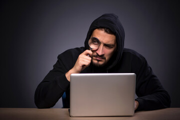 Young male hacker on grey background