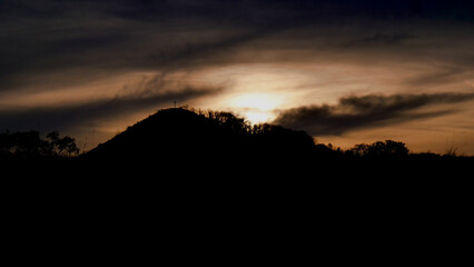 Radobýl hill with a huge cross on top, with a setting sun. Beautiful horizon line with tree...