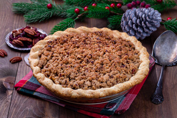 Freshly baked American apple cranberry pie, topped with crumbled dough and pecan, in baking dish