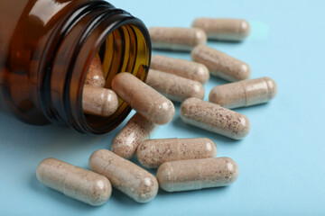 Gelatin capsules and bottle on light blue background, closeup