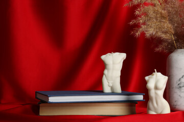 Composition with beautiful female and male body shaped candles on red fabric