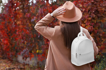 Young woman with stylish white backpack in autumn park, back view