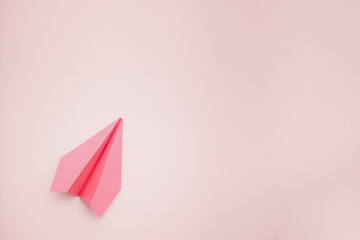 airplane made with pink colored paper on light yellow color