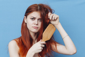 pretty woman combing naughty hair blue background