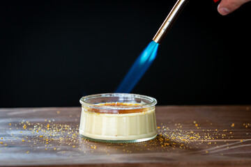 Tasty Dish of Creme Brulee French Dessert in a Glass Bowl With a Blow Torch