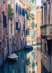 A quiet Venice Italy canal with two boats as the sun sets.