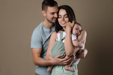 Happy family. Couple with their cute baby on beige background