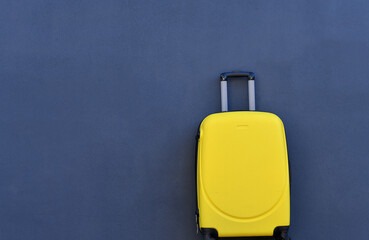 Yellow suitcase on grunge dark grey background, holiday concept. Copy space