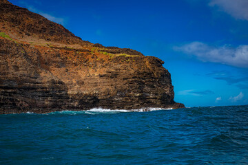 Fototapeta na wymiar 2021-11-01 ROCKY SHORE AND CLIFFS ALONG THE NA PALI COAST ON KAUAI HAWAII WITH A BRIGHT BLUE SKY