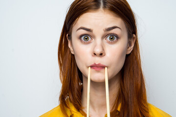 woman eating sushi with japanese chopsticks posing light background