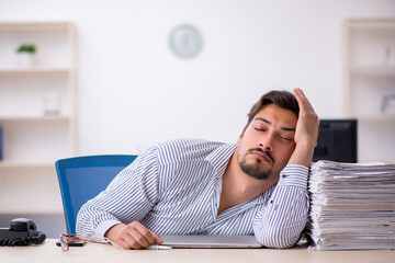 Young male employee and too much work in the office