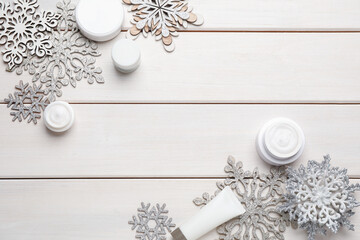 Fototapeta na wymiar Flat lay composition with cosmetic products and snowflakes on white wooden table, space for text. Winter skin care
