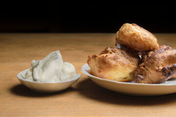 profiteroles and plate with sweet cream on wooden table