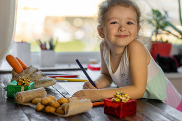 child writing letter on traditional Dutch holiday Sinterklaas. in Europe, Netherlands, Belgium girl put in in boot, shoe a carrot for Santa horse, gifts, pepernotin chocolate sweet cookies.
